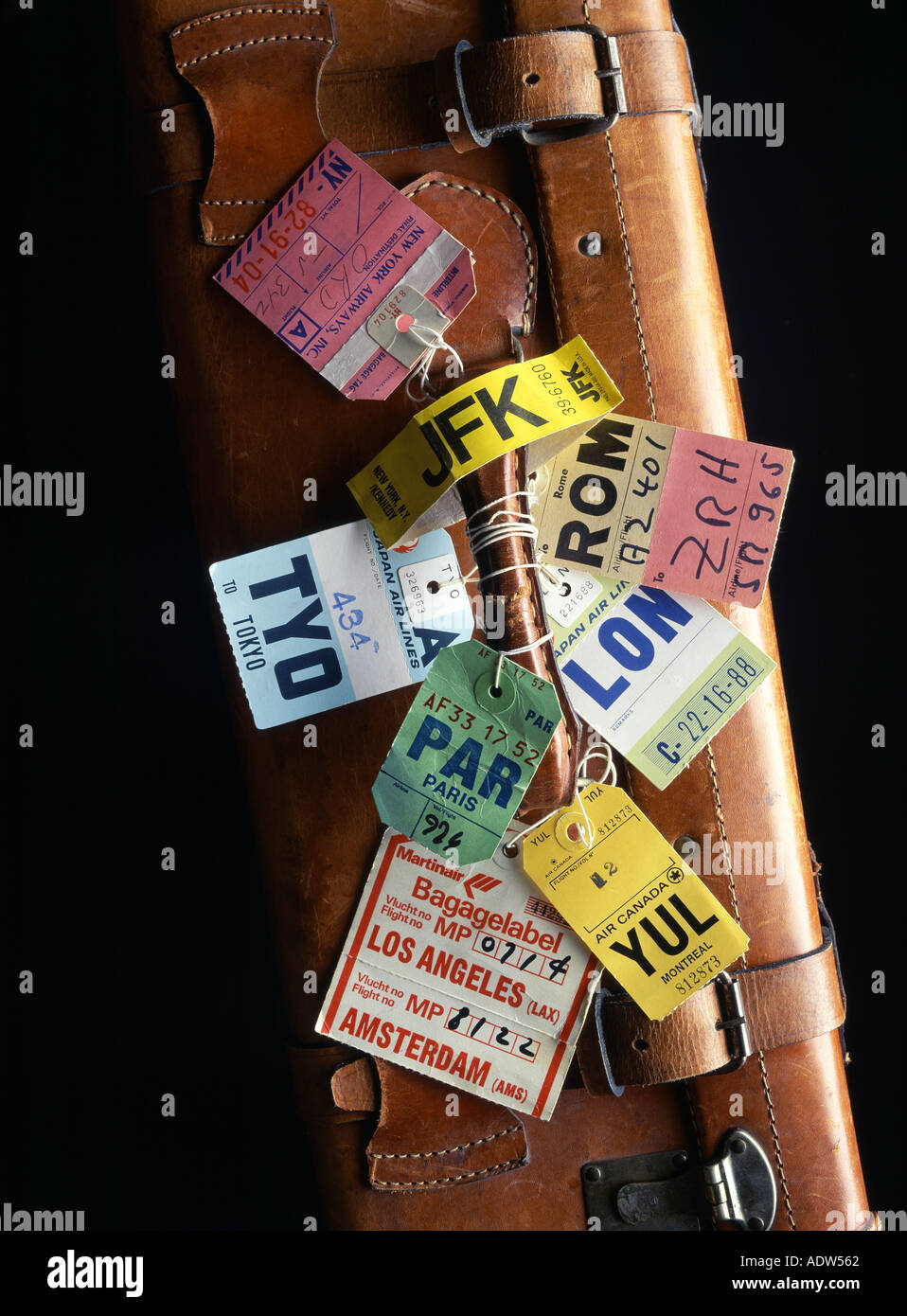 AIRLINE LUGGAGE TABS AROUND THE HANDLE OF A BROWN LEATHER SUITCASE Stock Photo