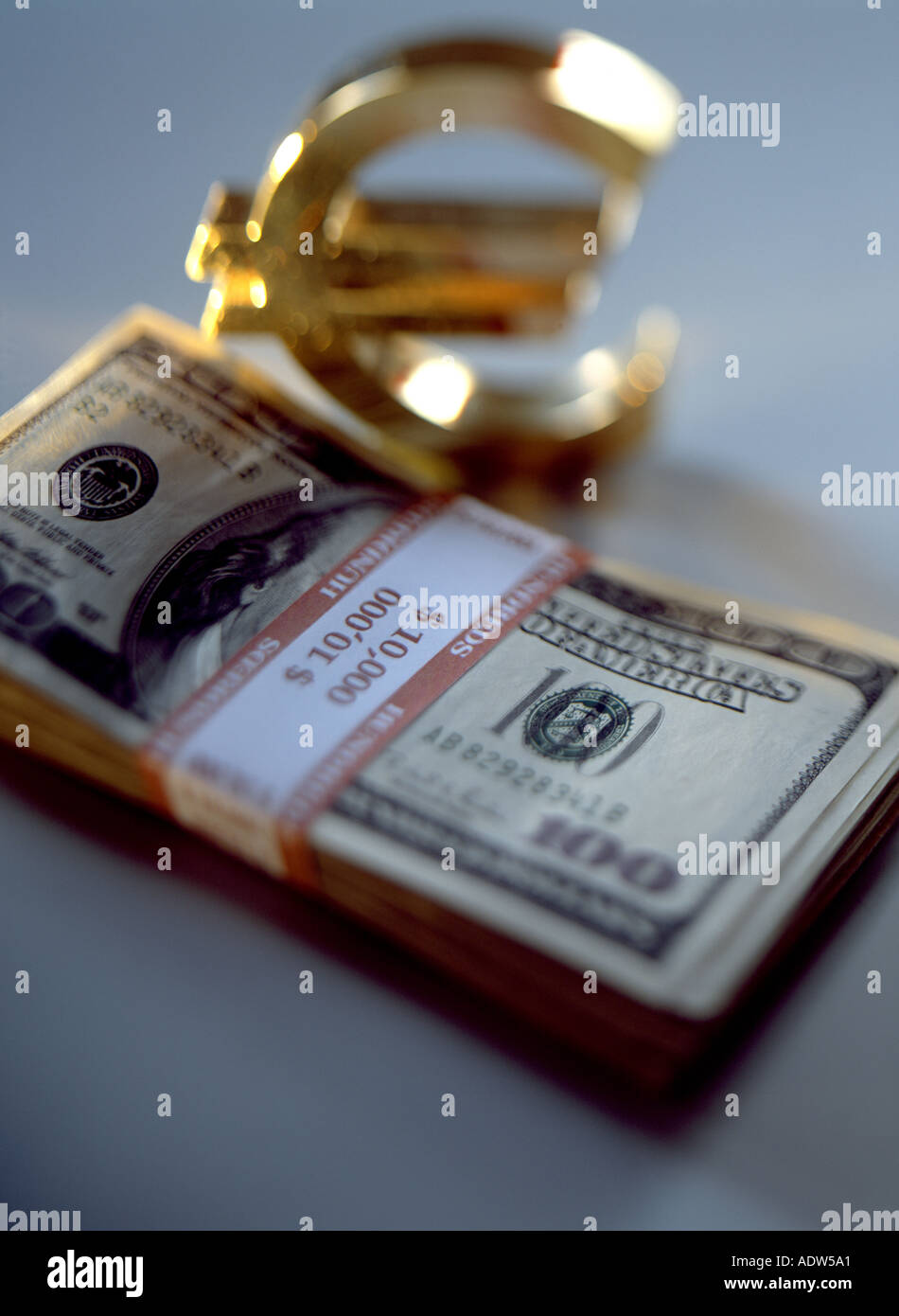 WAD OF 100 US DOLLARS BANKNOTES AND GOLDEN EURO CURRENCY SIGN Stock Photo