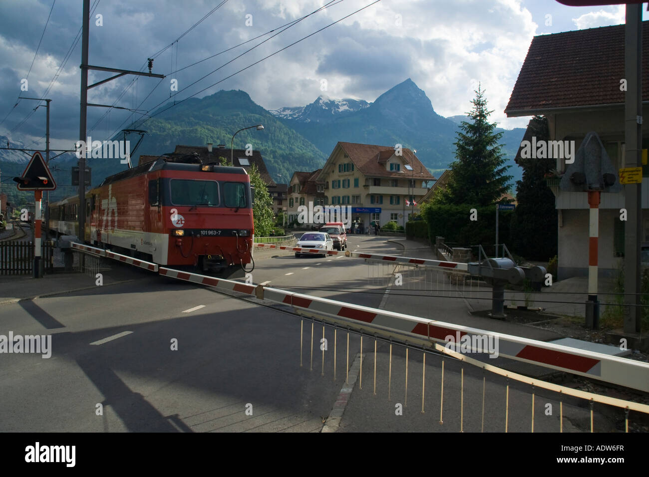 Train down from Brünigpass at railroad crossing in Giswil, Obwalden, Central switzerland Stock Photo