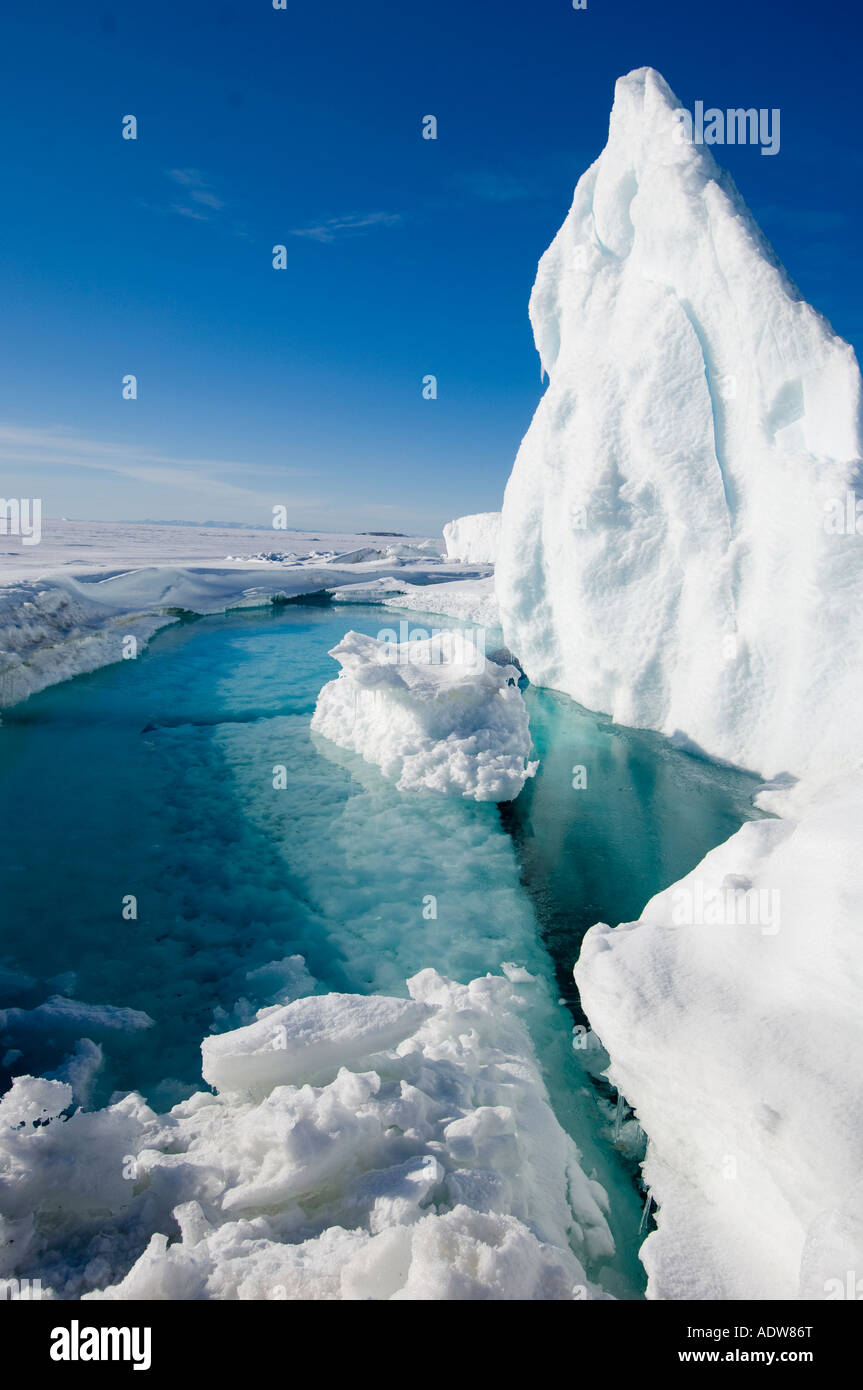 Meltwater pool at base of iceberg with crack in the ocean sea ice at base in spring. Stock Photo
