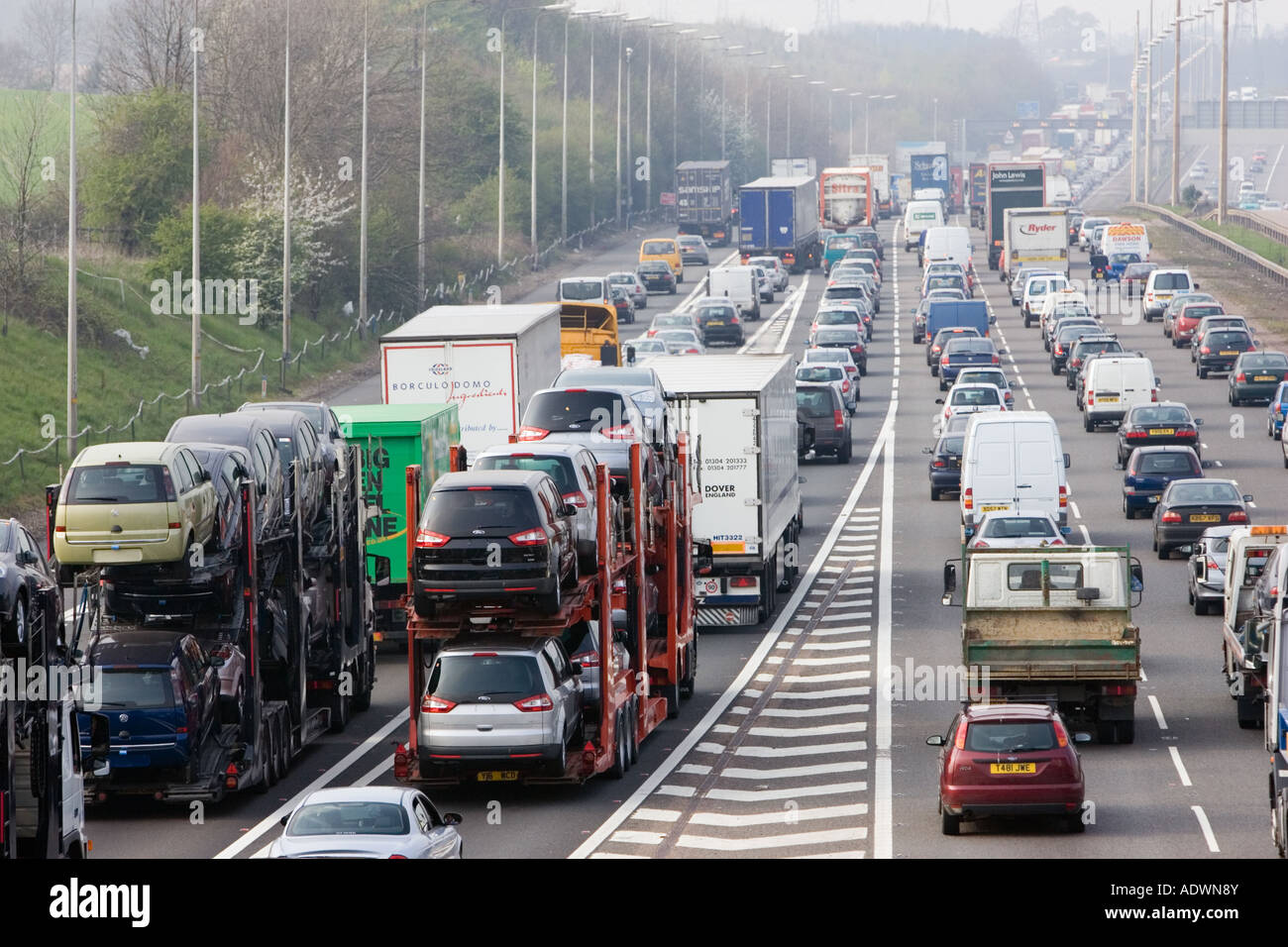 Car transporter lorries travelling among congested traffic on M1 motorway in Hertfordshire United Kingdom Stock Photo