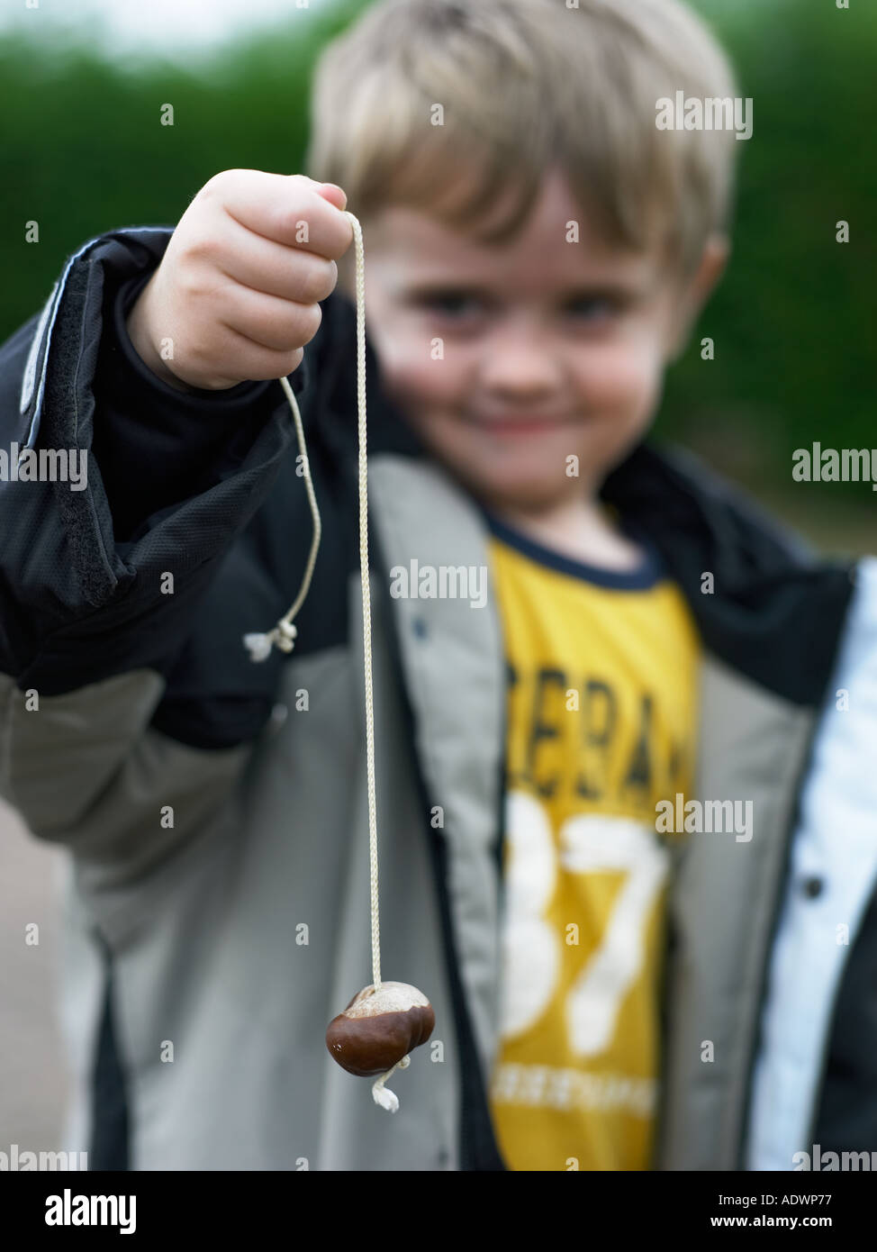 young boy in coat playing conkers Stock Photo