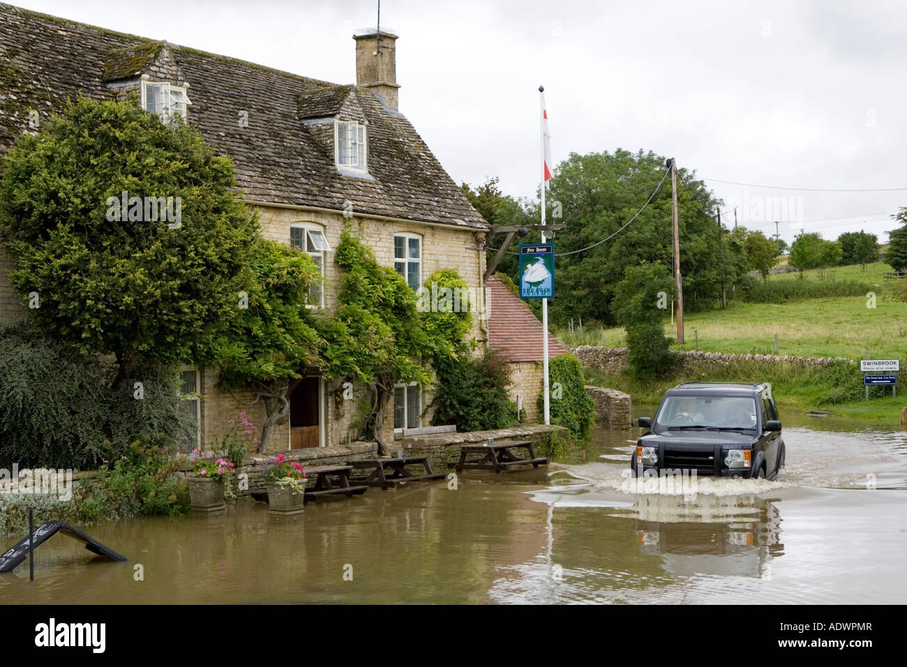 Four wheel drive car drives through flooded road in Swinbrook Oxfordshire England United Kingdom Stock Photo
