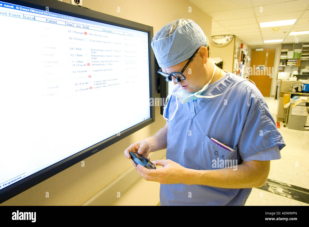 surgeon checking his pager or cell phone in hallway of hospital Stock Photo