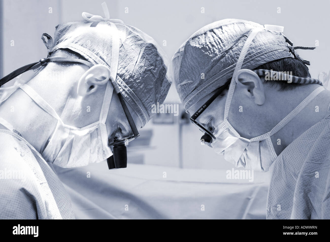 portrait of 2 two vascular surgeons working closely together in operating room theater theatre Stock Photo