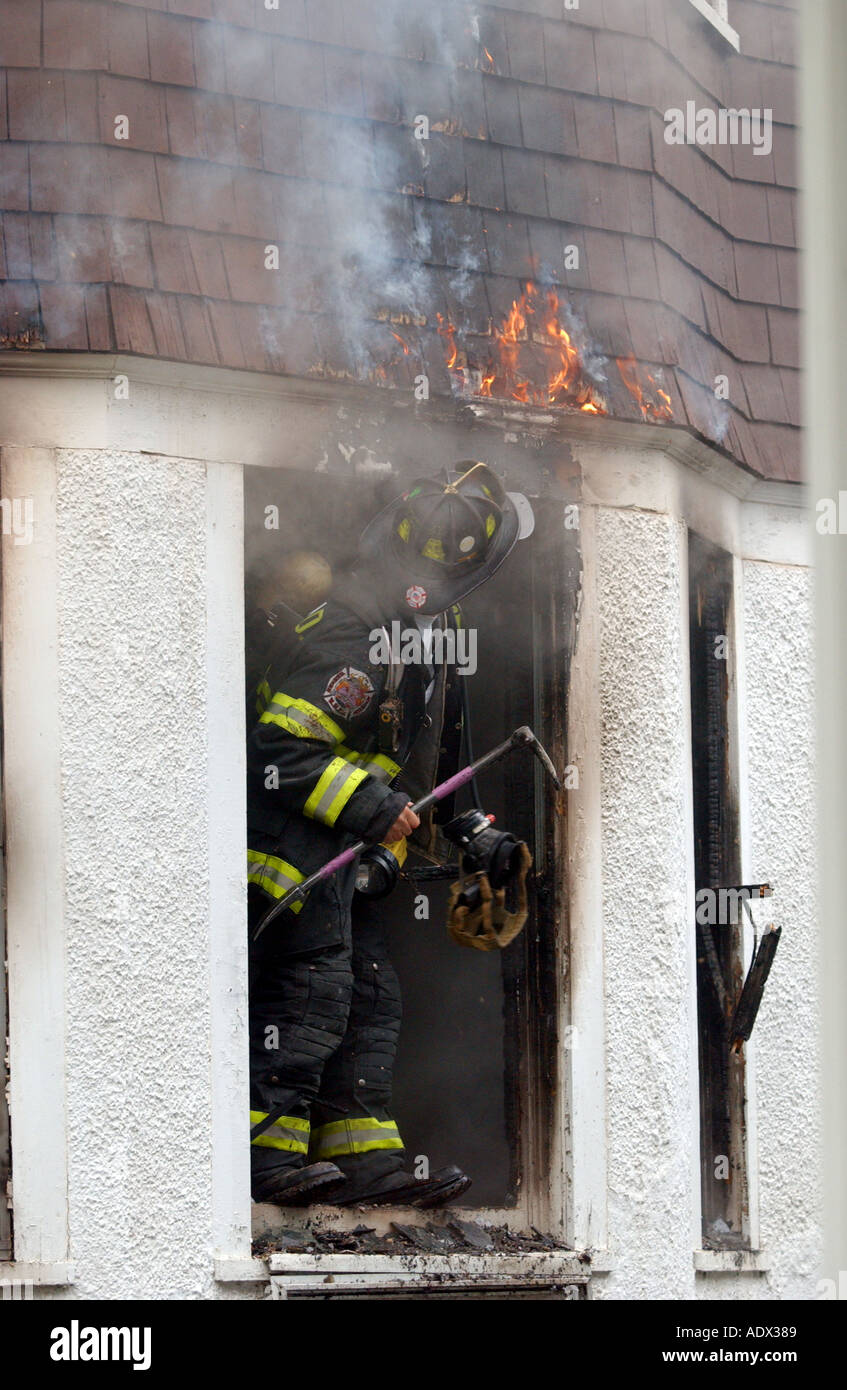 Firemen firefighters looking for a fire as it burns above them during a house fire emergency Stock Photo