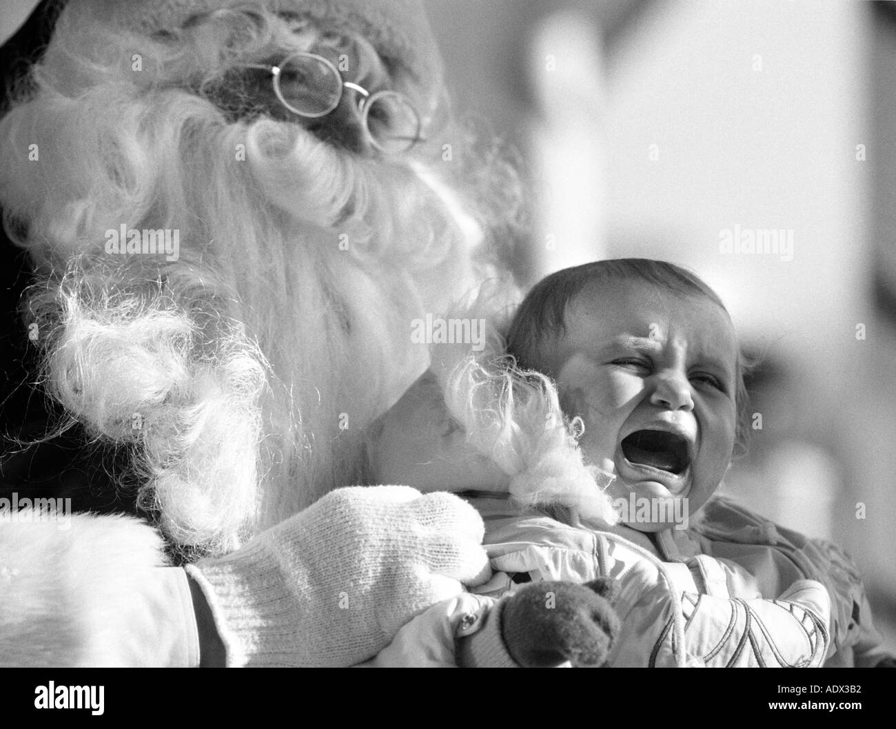 Fake santa claus holding crying baby scared child humor st nick saint nick christmas party Stock Photo