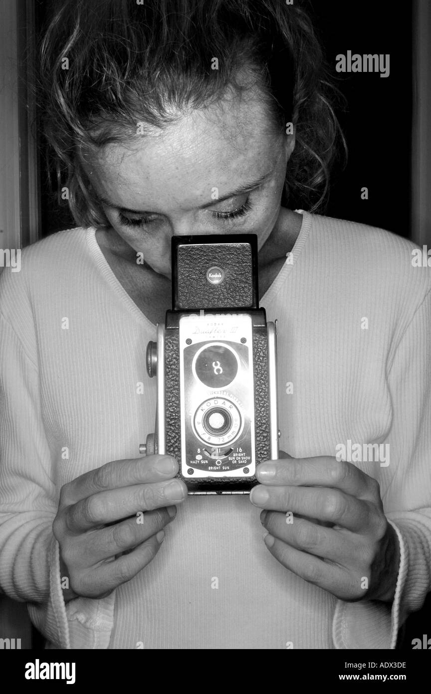 Woman taking picture with old fashioned camera holding camera antique camera in front of face Stock Photo