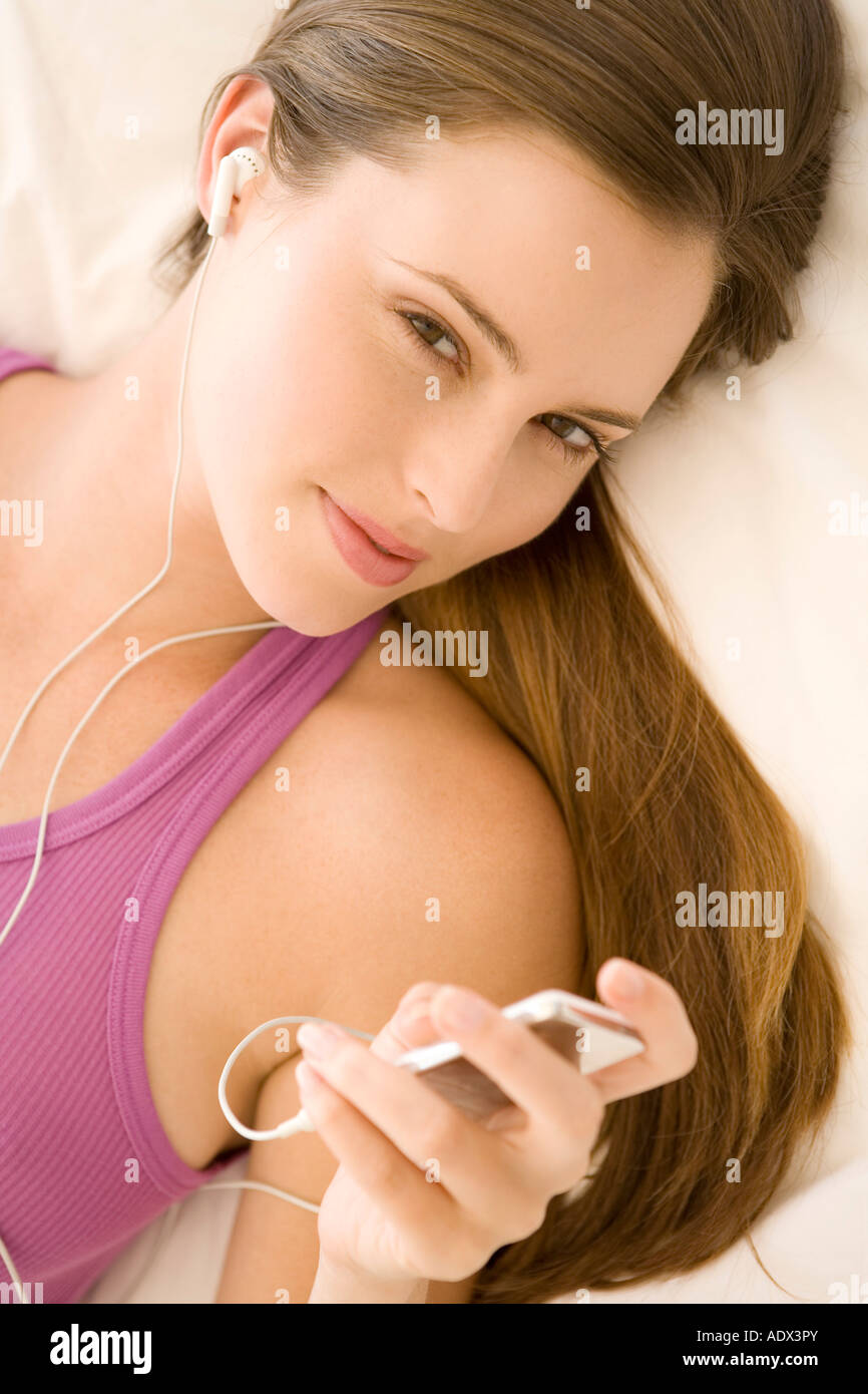 Young woman lying on bed listening to music Stock Photo - Alamy