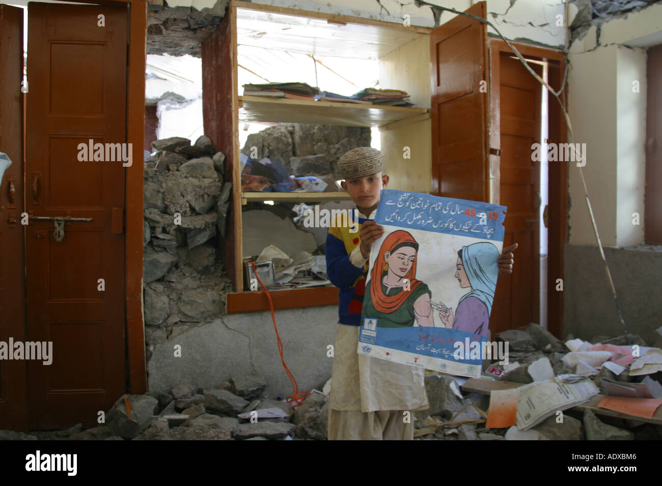 Boy in a destroyed clinic where he holds a campaign poster for tetanus vaccination Stock Photo