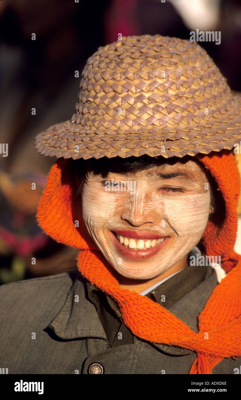 Smiling Burmese girl wearing a straw hat with tanaka  painted on her cheeks as sun protection and decoration. Stock Photo