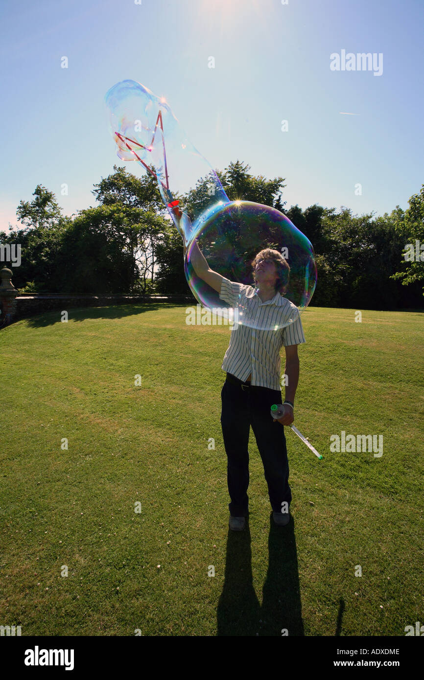 Man in mid twenty's blowing large bubbles outside using a bubble wand. Stock Photo