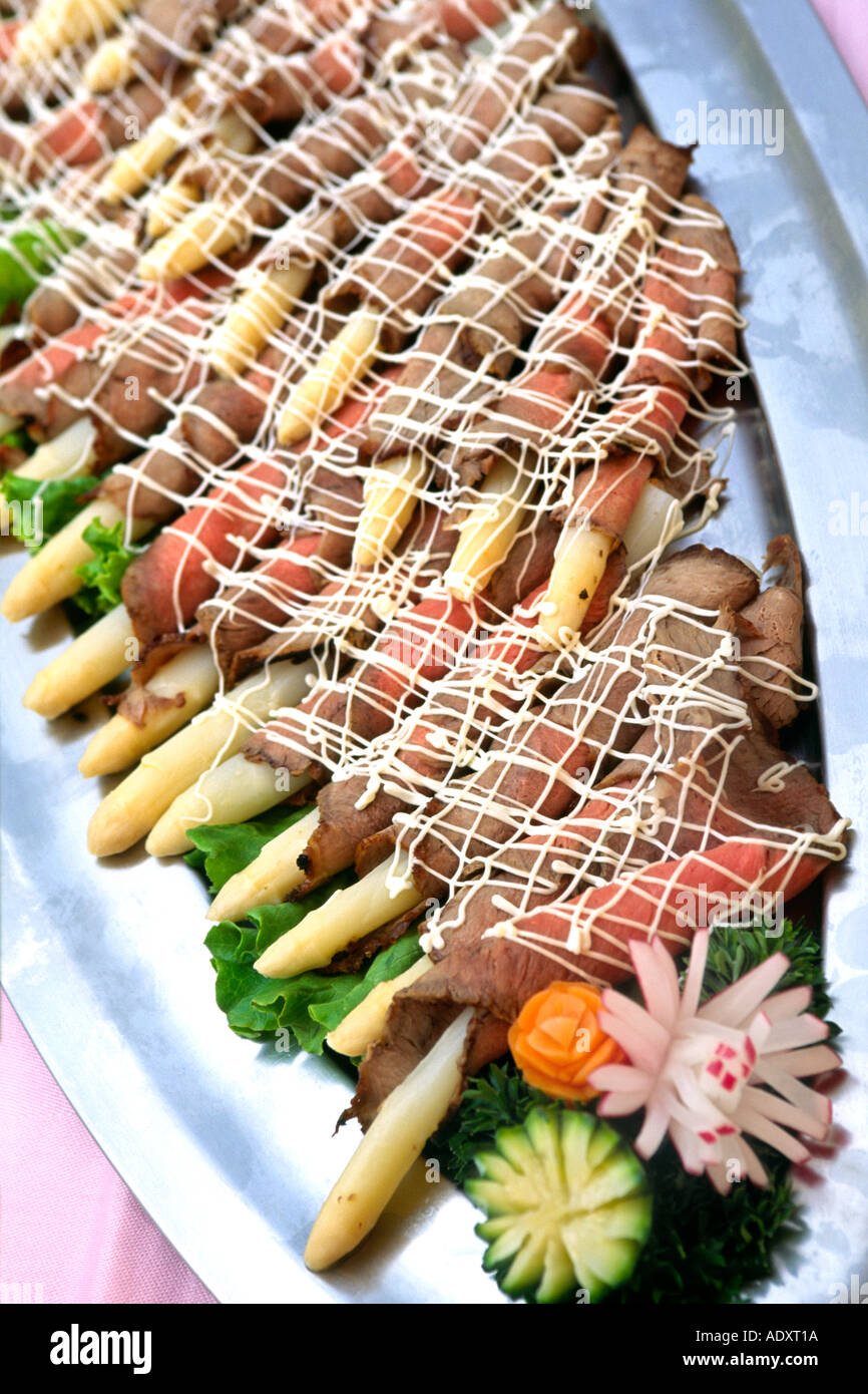 Close-up of a dish of asparagus rolled in roast beef. Stock Photo