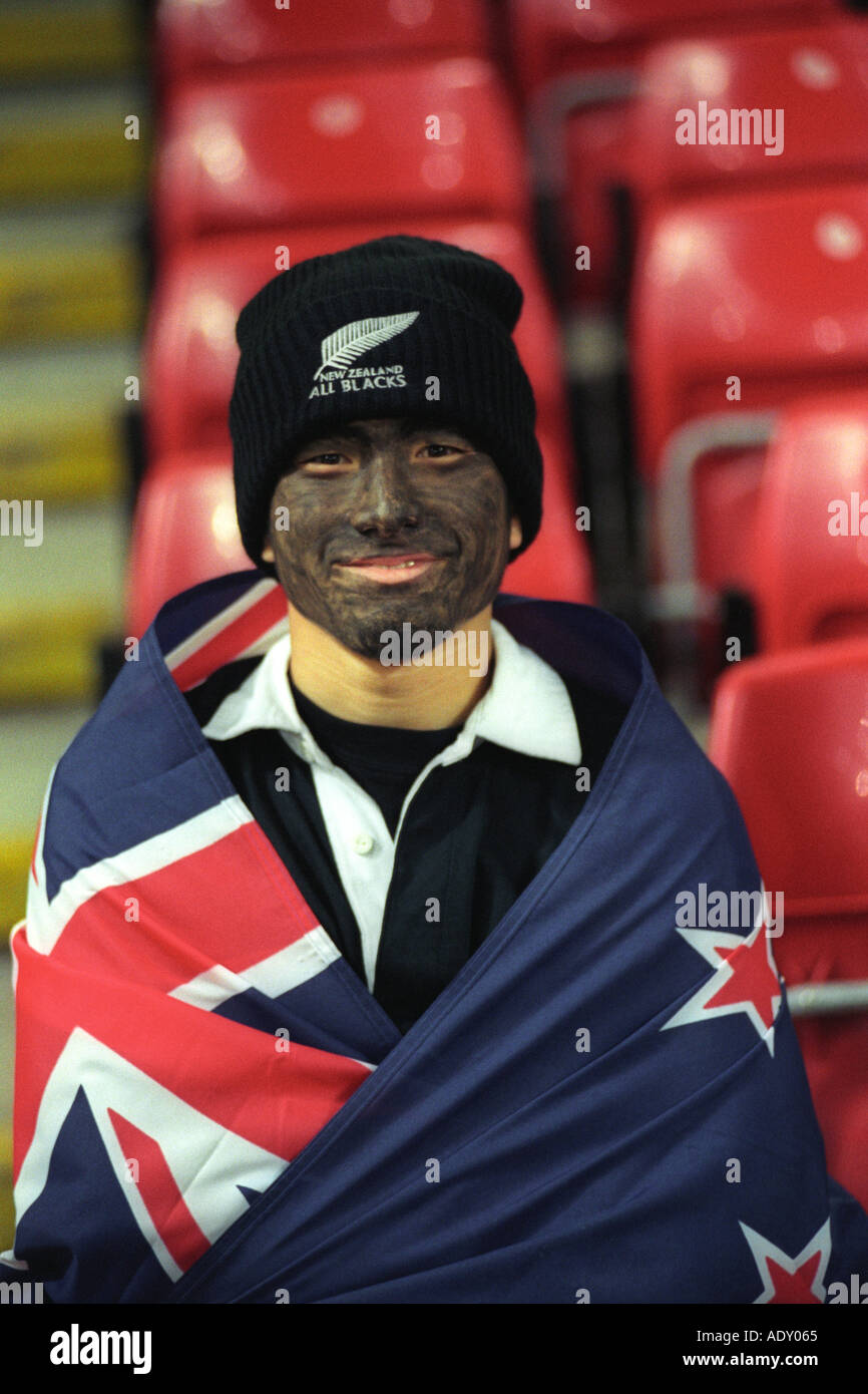 New Zealand rugby fan wrapped in flag and face painted black at Millennium Stadium Cardiff Wales UK for an international match Stock Photo