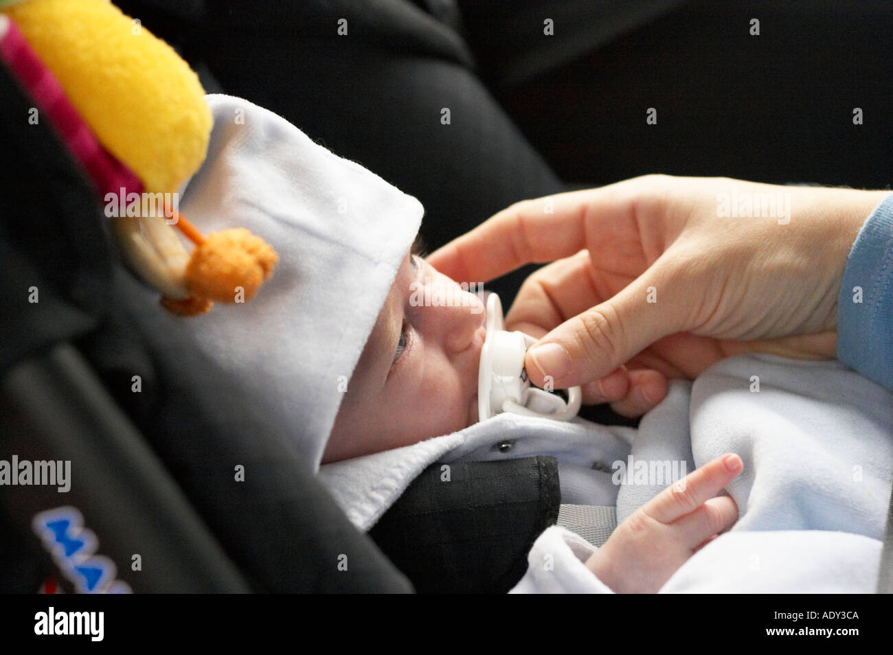 baby in child safety seat / mother giving comforter to the baby Stock Photo