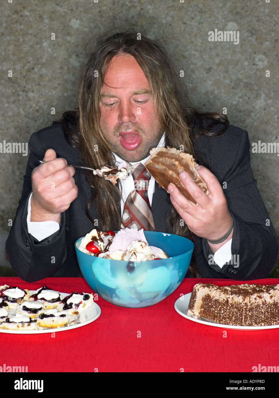 Long haired fat man eating stuffing himself with cake and ice cream Stock  Photo - Alamy