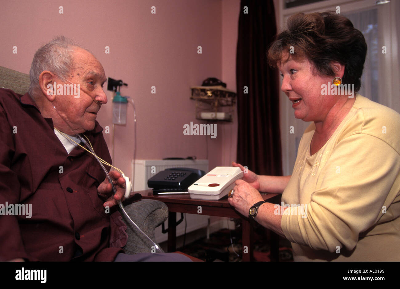 Social services staff explaining to elderly man use of panic machine in ...