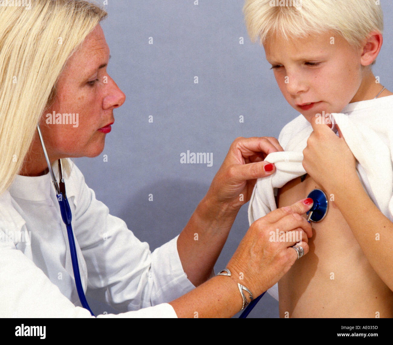 Female doctor ist listening at the heart of a little boy Stock Photo