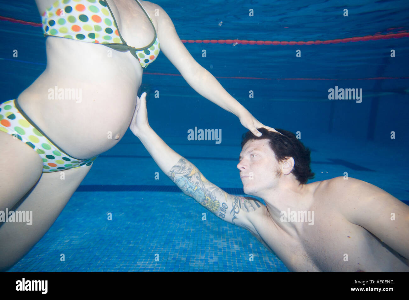 Pregnant Couple Swimming in Pool Couple therapy Stock Photo