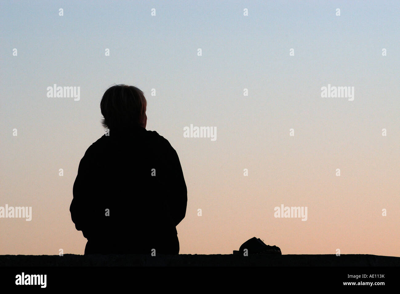 Silhouette of a sitting woman in the evening Stock Photo - Alamy