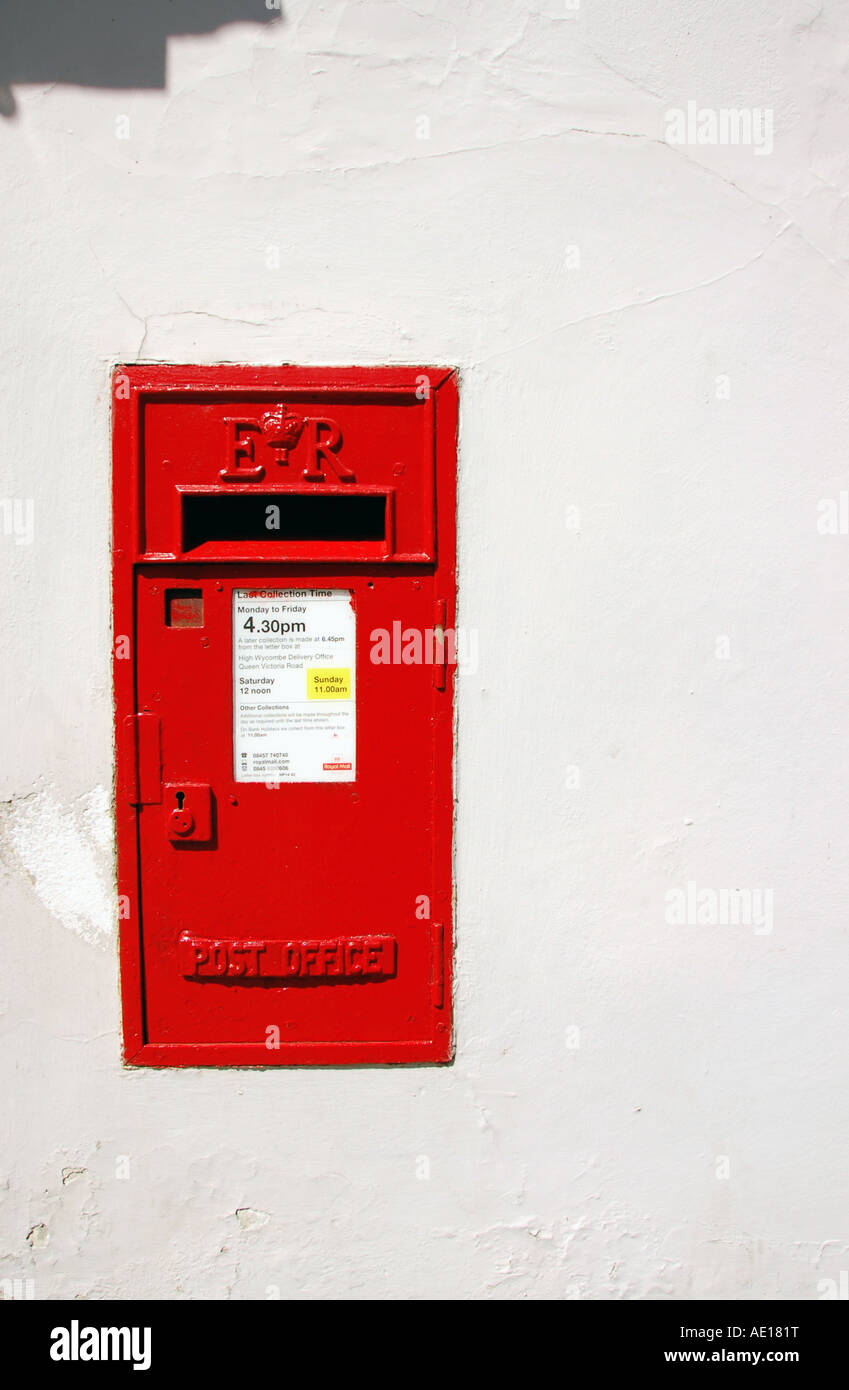 Traditional British red Royal Mail post office box built into white wall Stock Photo