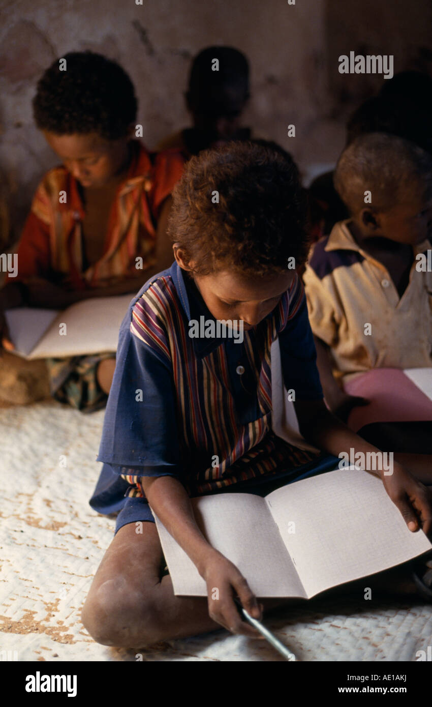 SOMALIA East Africa Tula Bawayo Schoolchildren sitting on ground in classroom reading in area near Mandera devastated by war. Stock Photo