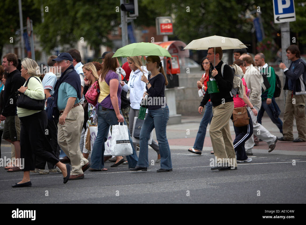 people crossing a busy intersection on oconnell street dublin during rush hour some carrying umbrellas Stock Photo