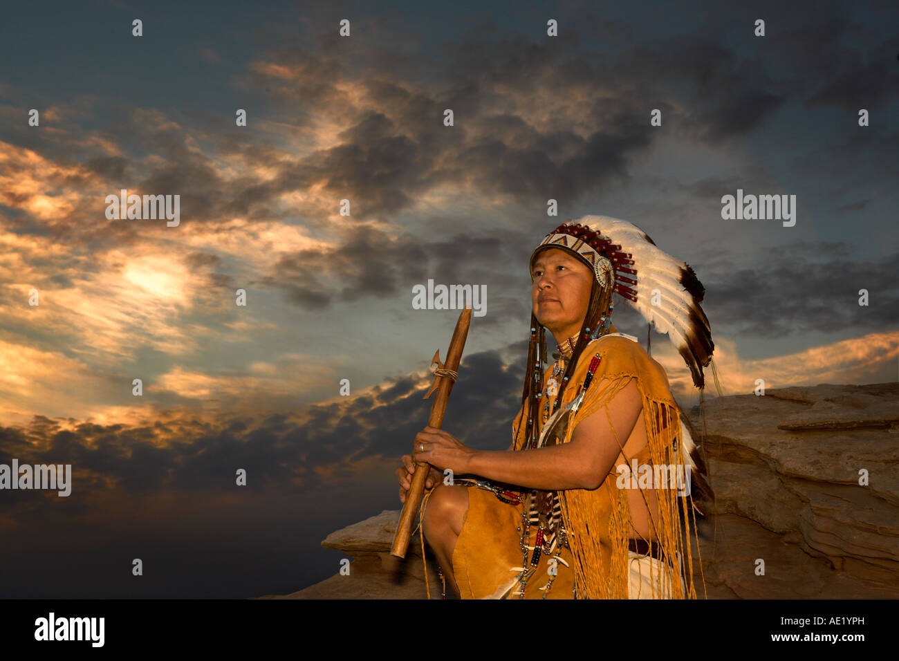 Native American Indian man with cultural outfit uniform headdress feathers design patterns leather band nature sunset sunrise Stock Photo