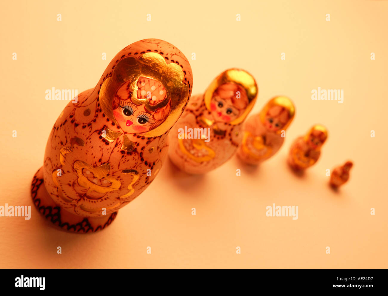 FIVE GOLD RUSSIAN DOLLS ON YELLOW BACKGROUND Stock Photo