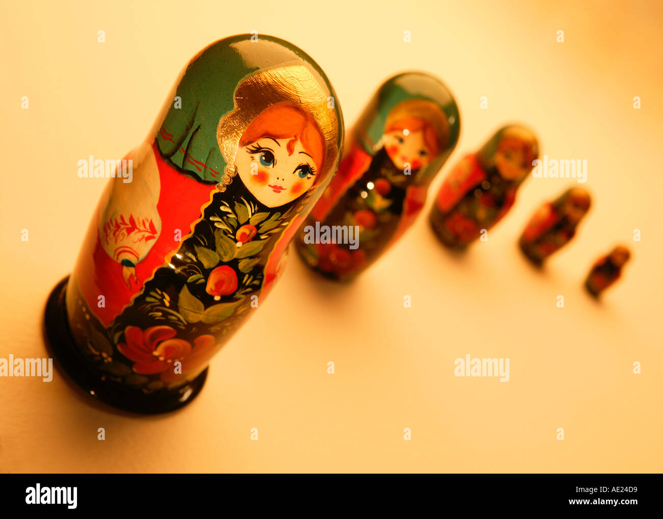 FIVE RED AND GREEN PAINTED RUSSIAN DOLLS ON YELLOW BACKGROUND Stock Photo