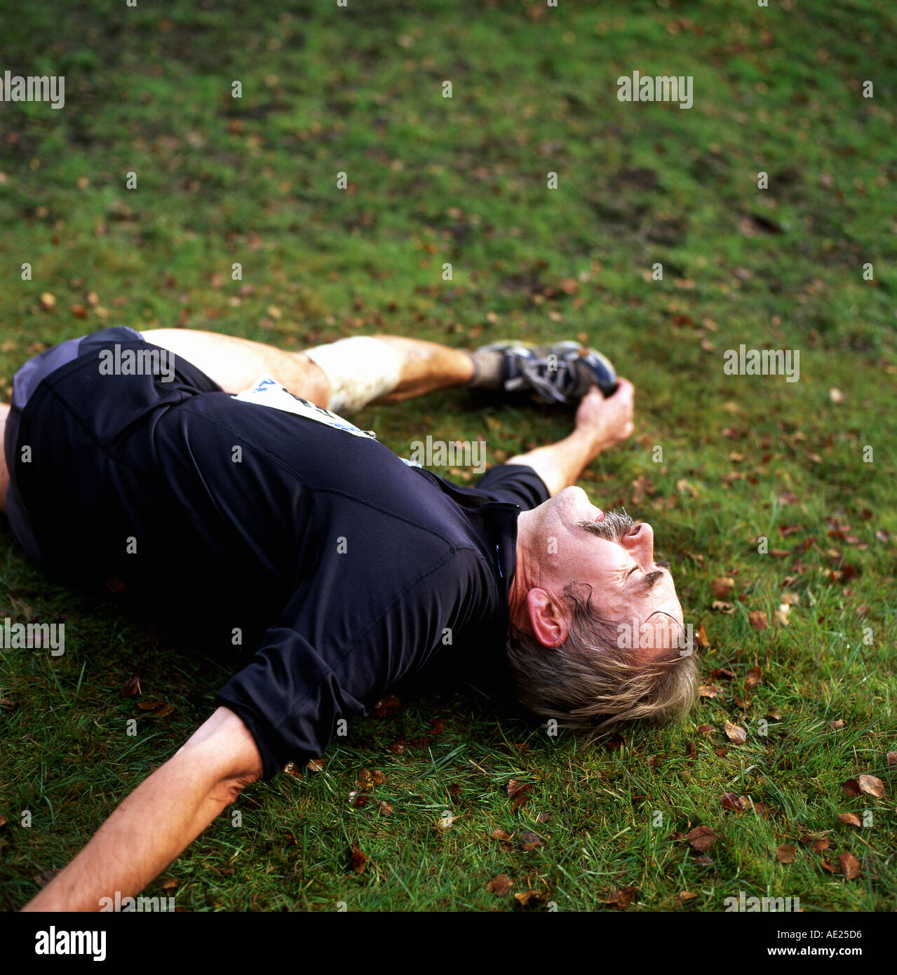 A man lying on the ground stretching limbs to relieve cramp pain after