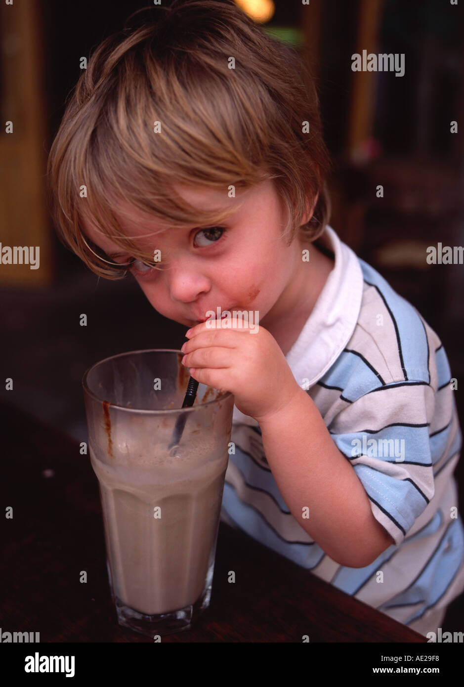 boy drink chocolate milkshake through straw from glass Stock Photo Alamy