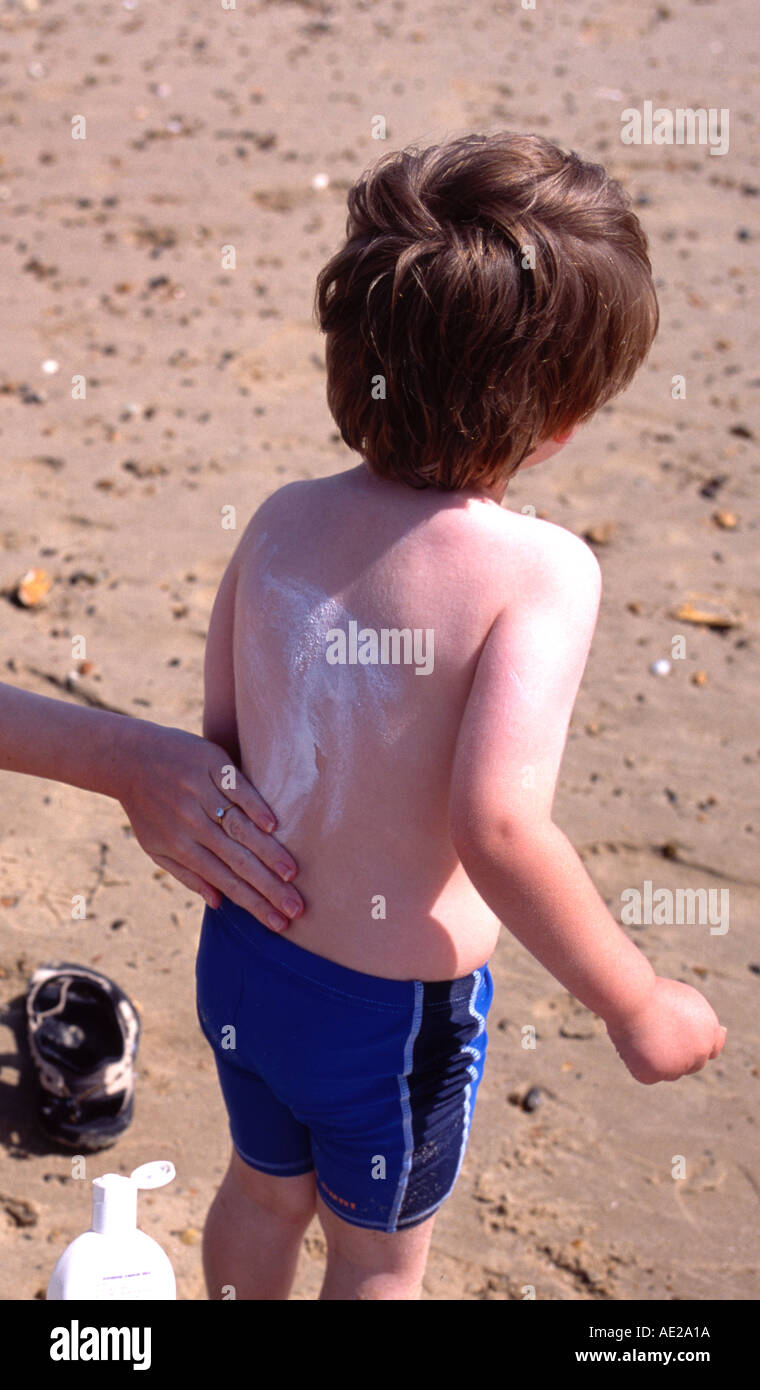 mother putting suntan lotion on chids back for protect from burning
