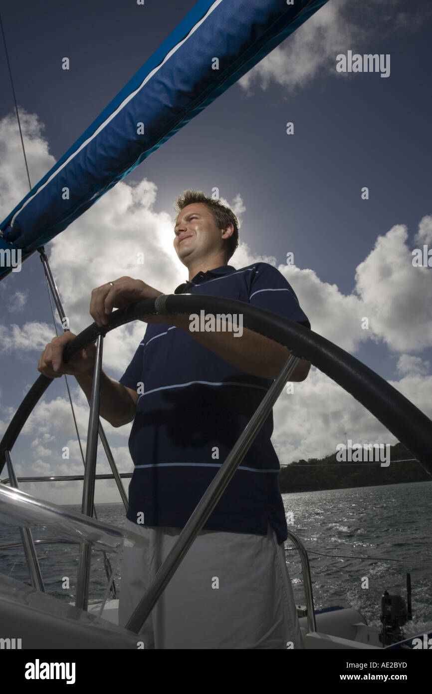 Contre jour shot of young man at the helm of a sailing yacht Stock Photo