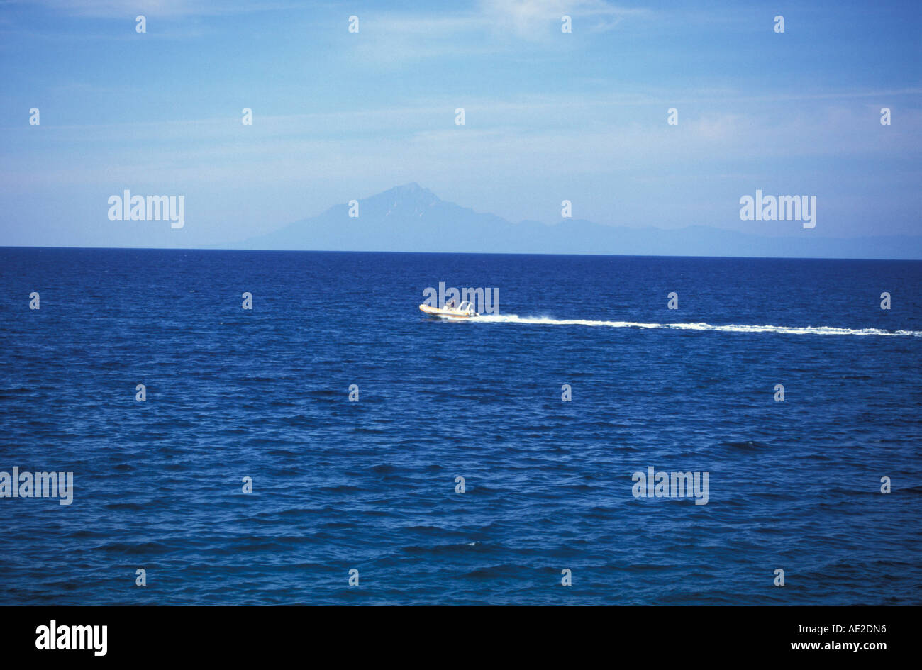 A power boat speeding across the water with Mount Athos on the horizon ...