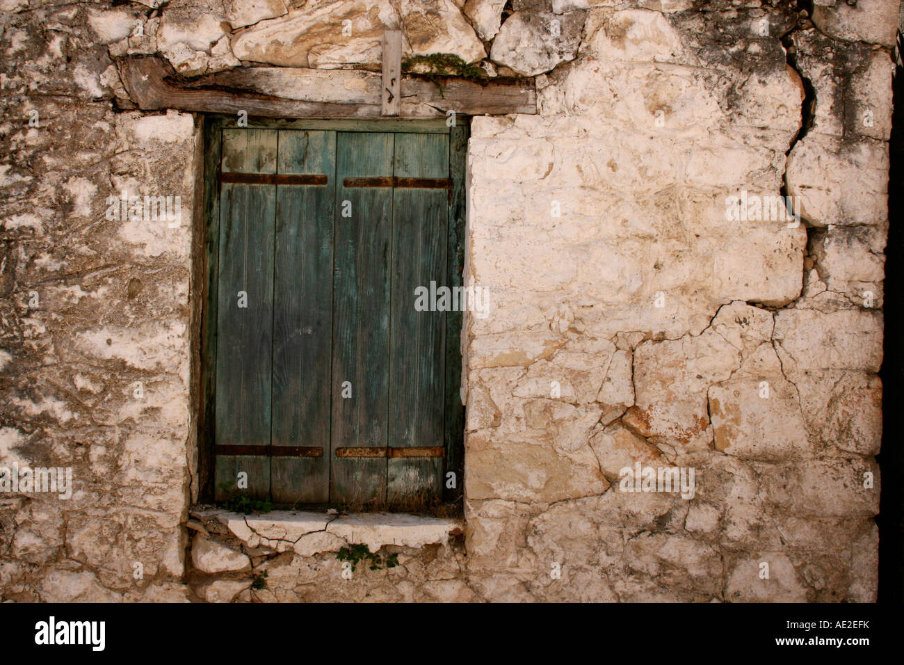 Green shutter over window with cracked stonework Karia Lefkas Greece Stock Photo