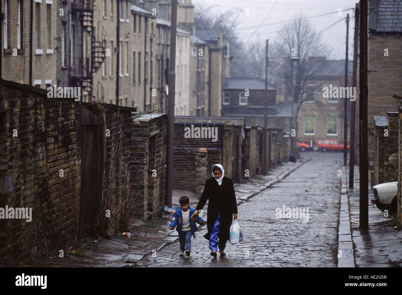 A muslim lady and her son walk down a cobbled back street in Bradford Yorkshire Stock Photo