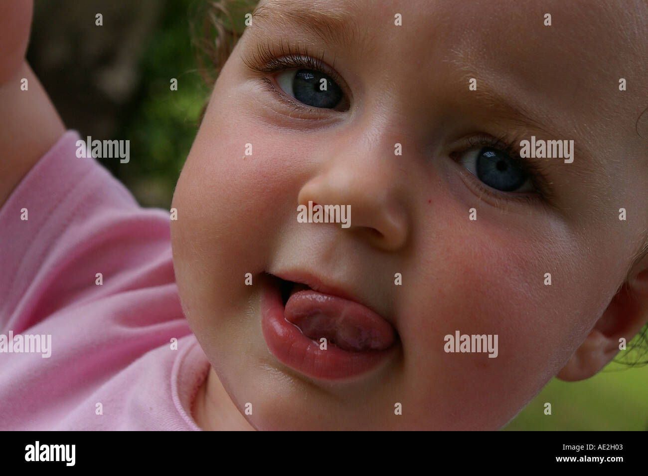 Baby little girl portrait closeup close up c u  poking tongue teething cheeky fun mischievous blue eyes eyed Stock Photo