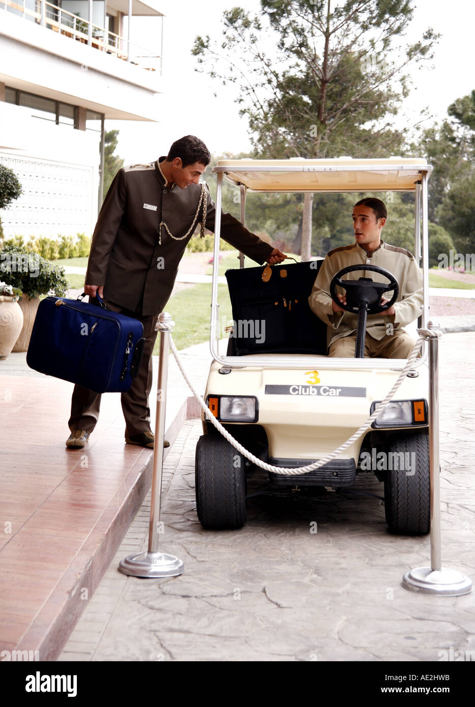 Bellboy driving hotel cart to deliver luggage to doorman Stock Photo