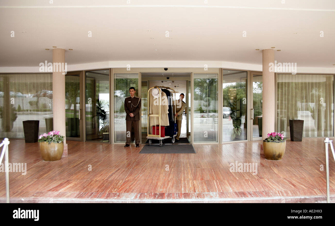 Bellboy delivering luggage to hotel with doorman standing by Stock Photo