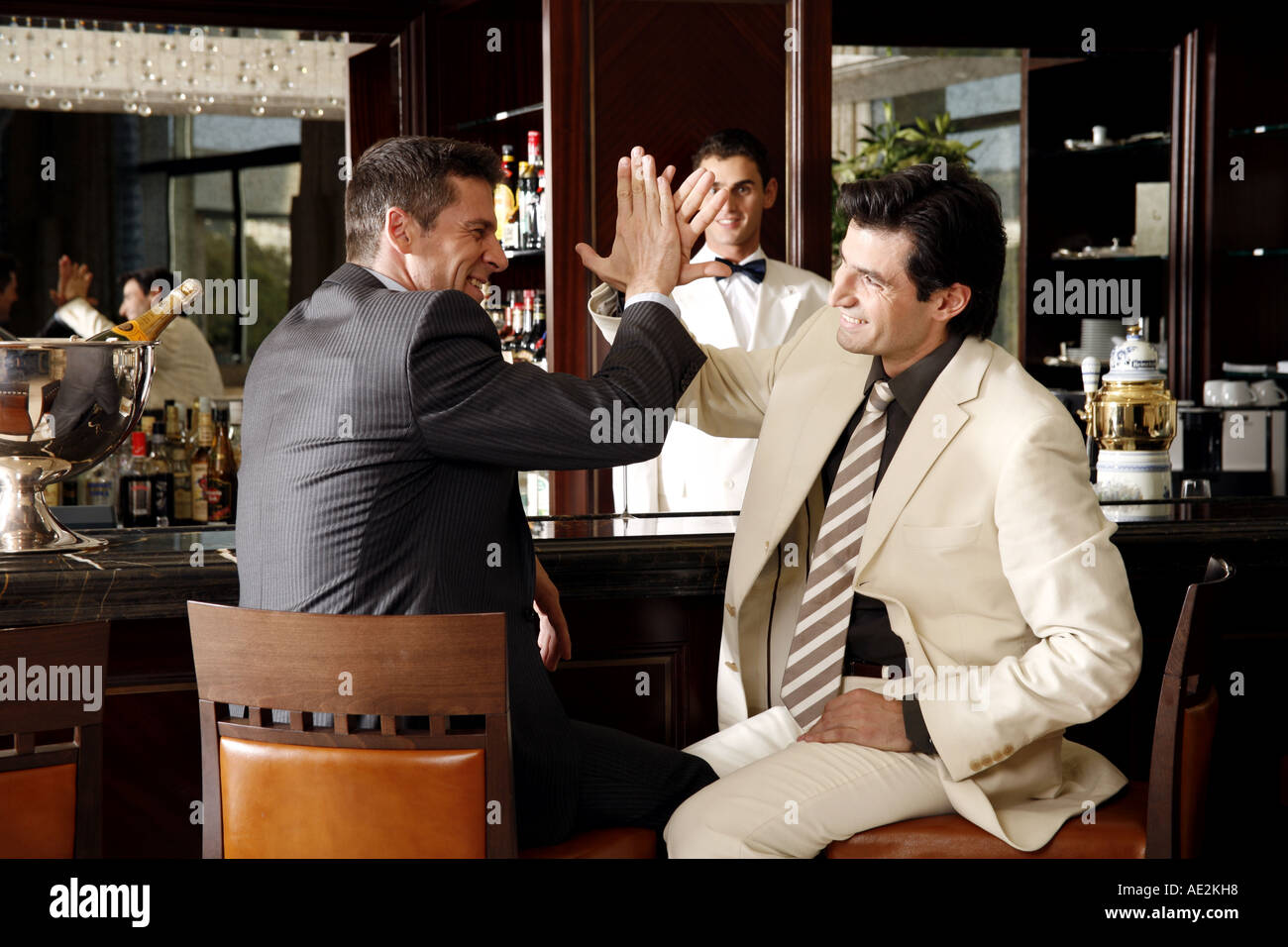 Two men slapping hands in agreement at a bar Stock Photo