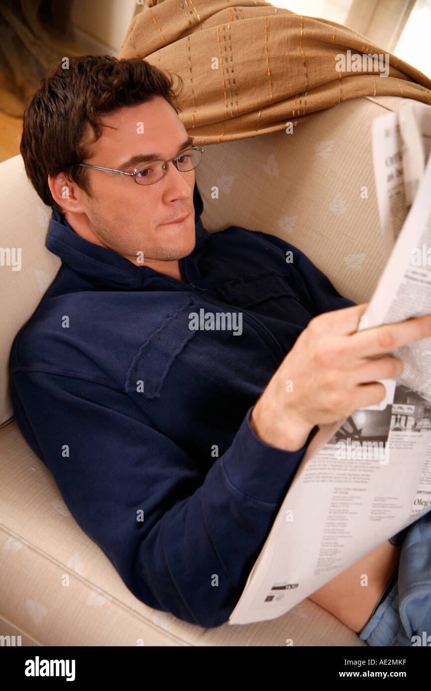 Young man reading a newspaper Stock Photo - Alamy