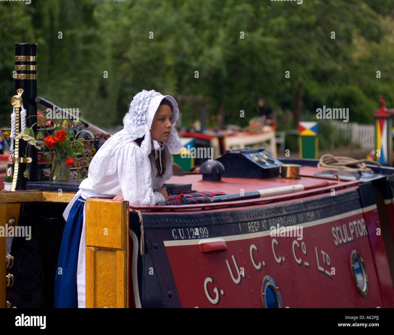 Traditional historic GUCC Ltd narrowboat Sculptor with girl in traditional working cut dress moored at Stoke Bruerne Stock Photo