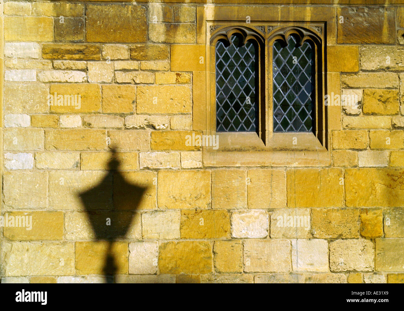 Shadow of historical streetlight on stone wall, church window Stock Photo