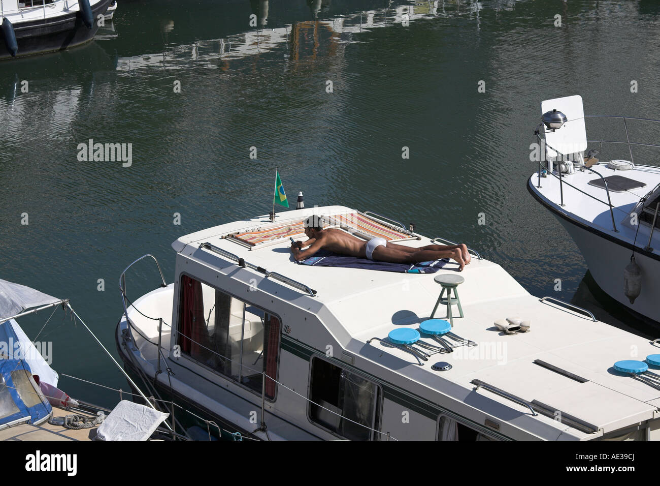Man sunbathing on boat in Port de Plaisance de Paris Arsenal Paris Stock Photo