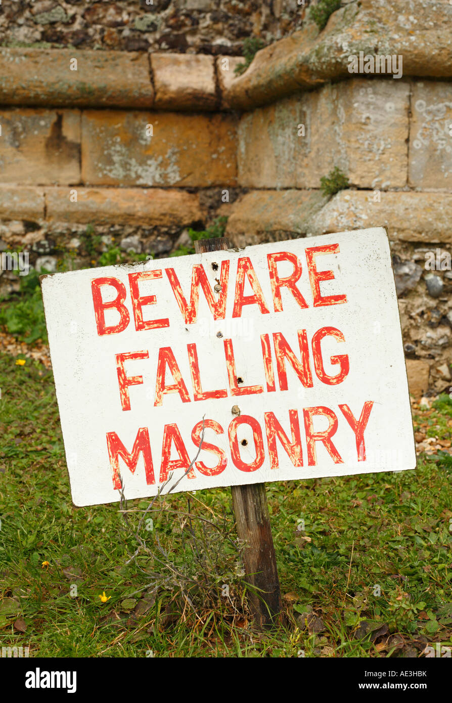 Beware falling masonry warning sign in a churchyard at Brancaster Norfolk. Stock Photo