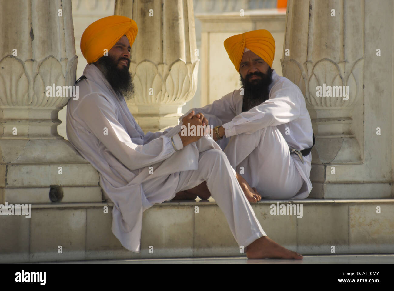Two Sikhs priests with orange turbans and white dress sitting under arcades, Golden Temple, Amritsar, Punjab state, India Stock Photo