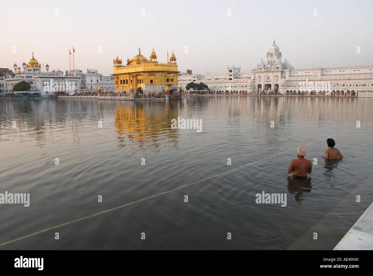 Two Sikh pilgrims bathing and praying in the early morning in holy pool ...