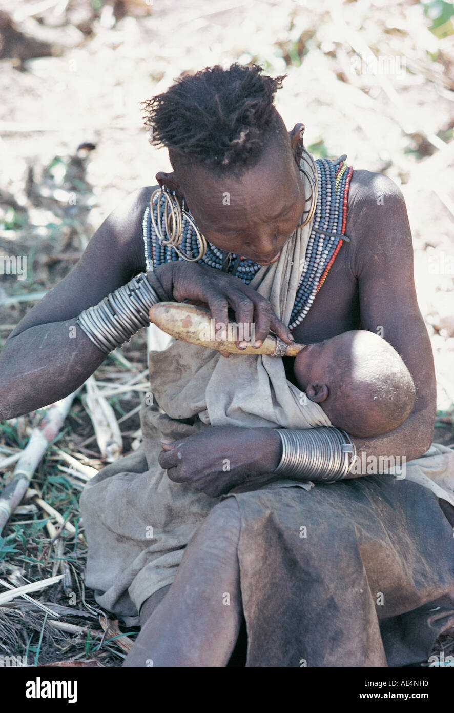 A Pokot grandmother feeding cows milk to her grandchild using a gourd Near Sigor northern Kenya East Africa Stock Photo