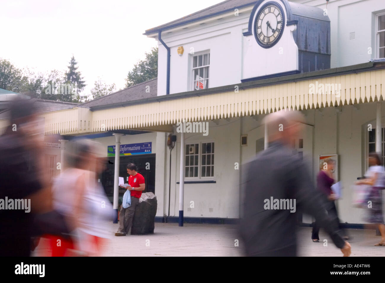 an individual reading a letter as blurred commuters rush for a train at Winchester station Stock Photo